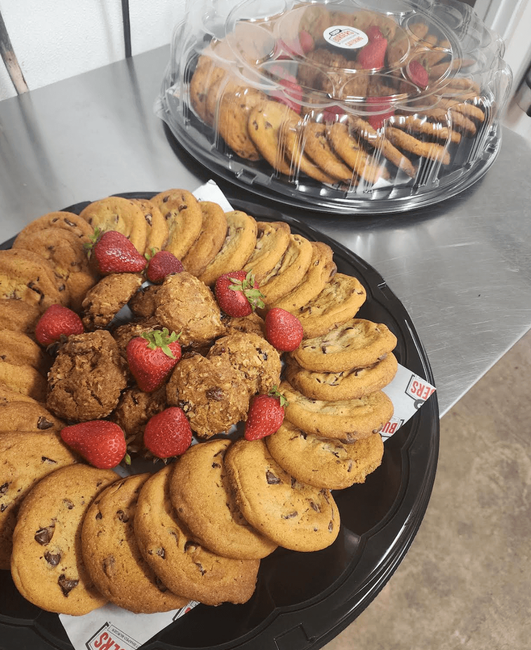 Platter of cookies with strawberries on a metal surface